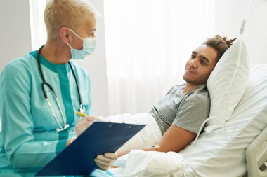 Tıbbi uzman not alırken hastayla konuşuyor.