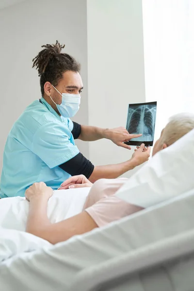Йоун медик, що демонструє рентгенівський знімок старого пацієнта — стокове фото
