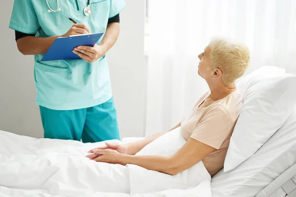Physician taking notes while communicating with patient — Stock Photo, Image