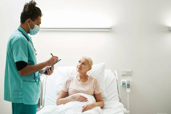 Arts opschrijven diagnose voor gepensioneerde in bed — Stockfoto