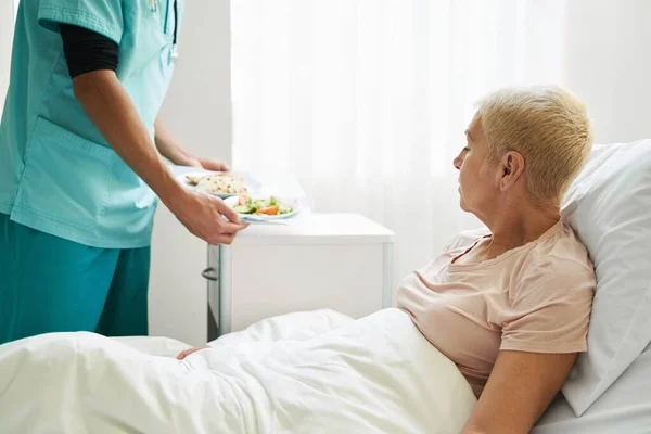 Trabajador médico trayendo comida al paciente envejecido — Foto de Stock