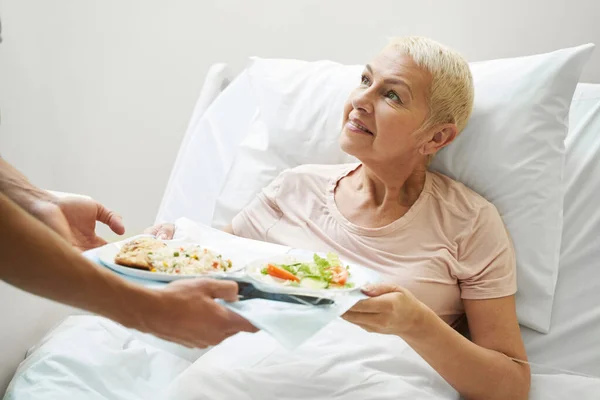 Aging lady getting meal tray from hospital employee — Foto de Stock