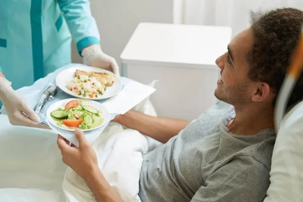 Happy man getting meal on tray from medical center worker — Zdjęcie stockowe