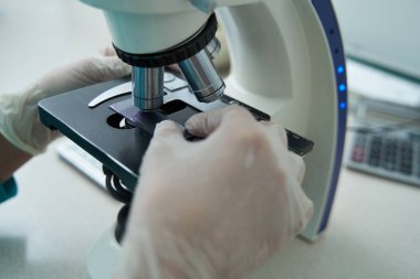 Klinikte mikroskopla test yapan bir kadın.