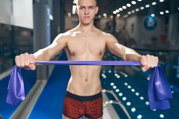 Young caucasian athletic man pulling resistance band by his hands — Photo