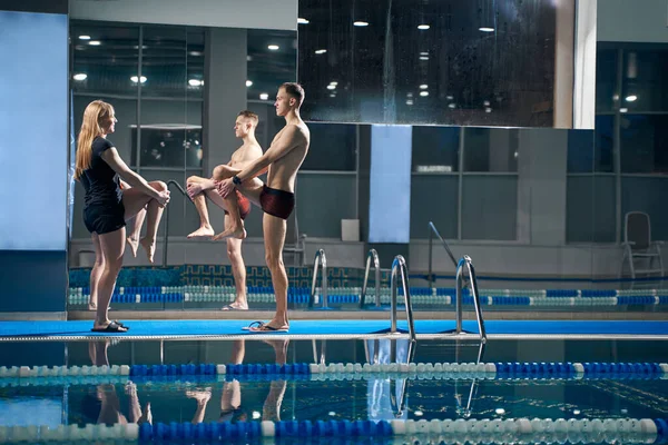 Bayan ve genç erkek egzersiz yapıyorlar, dizlerini kaldırıyorlar.