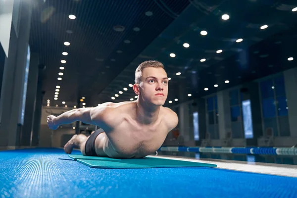 Athletic guy lying down on his stomach and spread his arms backward — Photo