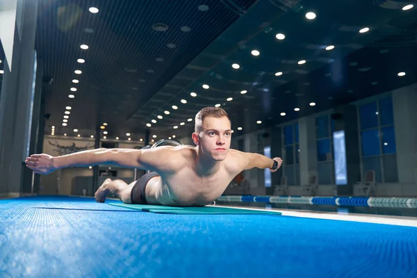 Male swimmer doing exercises on yoga mat swimming pool — Photo