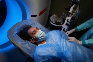 Genç adam MRI teşhisine başlamadan önce ilaç alıyor.