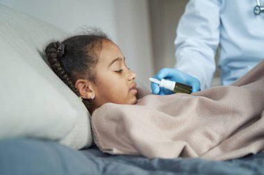 Afro-Amerikalı kız burnuna ilaç alıyor.