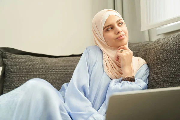 Mulher muçulmana sentada no sofá em casa — Fotografia de Stock