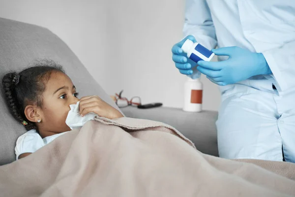 Afro american girl looks at the package of medicine in the hands of doctor — Stockfoto