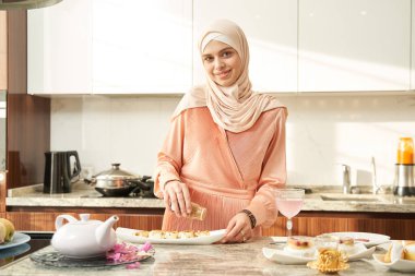 Cheerful Muslim woman cooking food for lunch at home