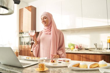 Mutfakta defter kullanan mutlu Müslüman kadın.