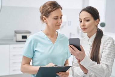 Güzellik doktoru ve kadın güzellik salonunda cep telefonu kullanıyor.