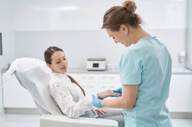 Kadın kozmetoloji kliniğinde cilt muayenesi yaptırıyor.