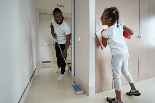 Adulto afro-americano uomo pulire pavimento in camera accanto alla figlia — Foto Stock