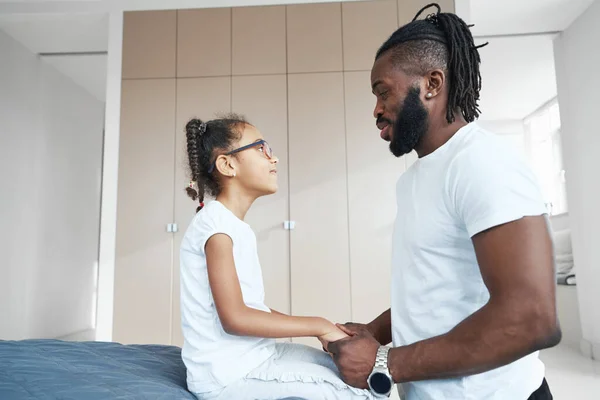 Adulto afroamericano uomo guarda la figlia e le tiene le mani — Foto Stock