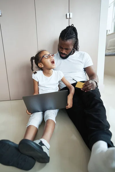 Figlia e padre usano il computer portatile sul pavimento in camera — Foto Stock