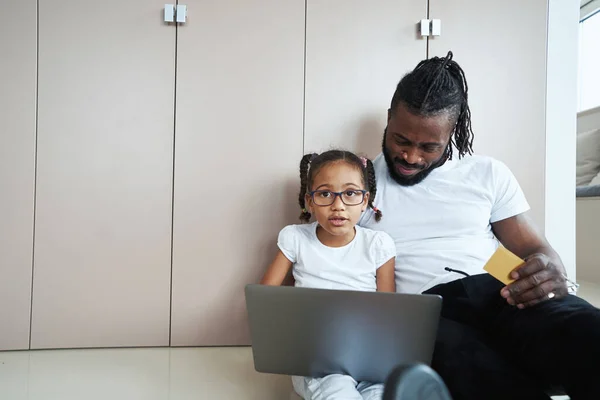 Tochter sitzt neben Vater mit Laptop auf Schoß — Stockfoto