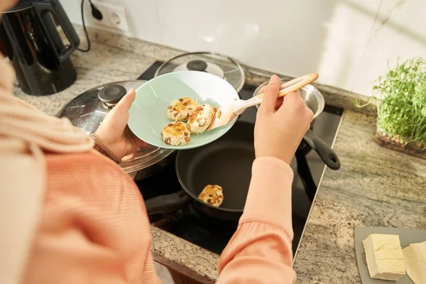 Cropped photo of young woman cooking cheese pancakes with raisins in kitchen — Fotografia de Stock