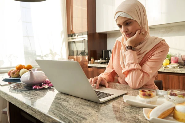 가정 부엌에서 노트북을 사용하는 이슬람 여성 — 스톡 사진