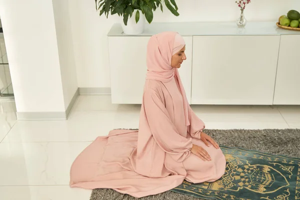 Muslim woman praying on prayer mat at home — 스톡 사진
