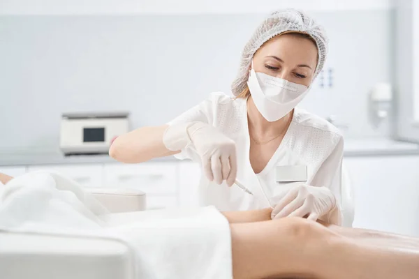 Dokter doet injectie in vrouw knie in schoonheidssalon — Stockfoto