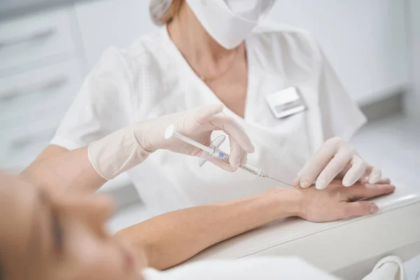 Kosmetička dělá injekce do ženské paže — Stock fotografie
