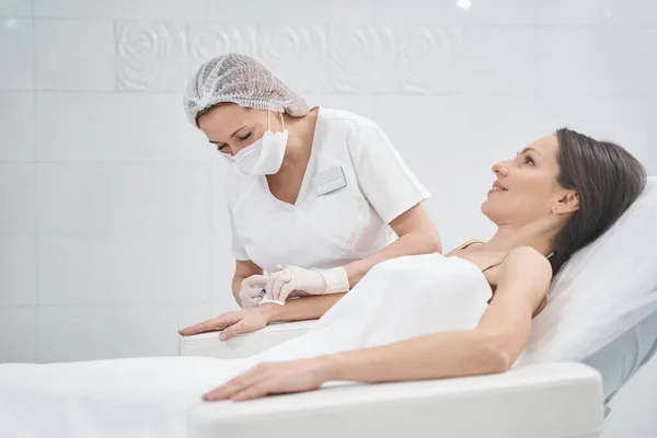 Smiling woman receiving arm injection in beauty clinic — Stockfoto