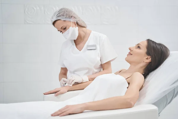 Улыбающаяся женщина получает инъекцию руки в косметологическую клинику — стоковое фото