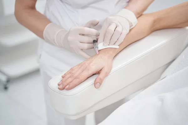Médico esteticista haciendo inyección en la mano de la mujer —  Fotos de Stock
