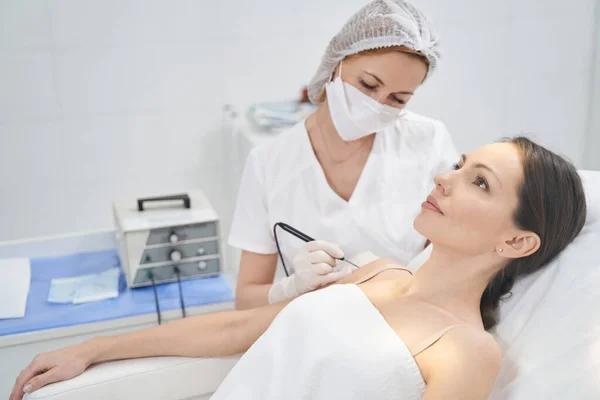 Doctor performing laser mole removal procedure in beauty clinic — Stockfoto