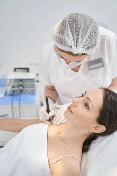 Kobieta leczona depilacją pieprzyka w klinice kosmetologii — Zdjęcie stockowe