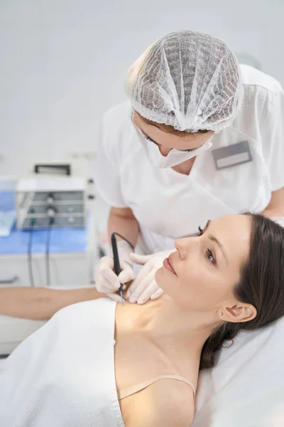 Donna che riceve un trattamento di rimozione talpa in clinica di cosmetologia — Foto Stock