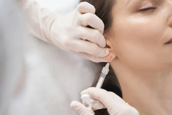 Doctor cosmetoloog het maken van schoonheid injectie in vrouw oor — Stockfoto