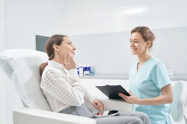 Vrouw in gesprek met dokter schoonheidsspecialiste in kosmetologie kliniek — Stockfoto