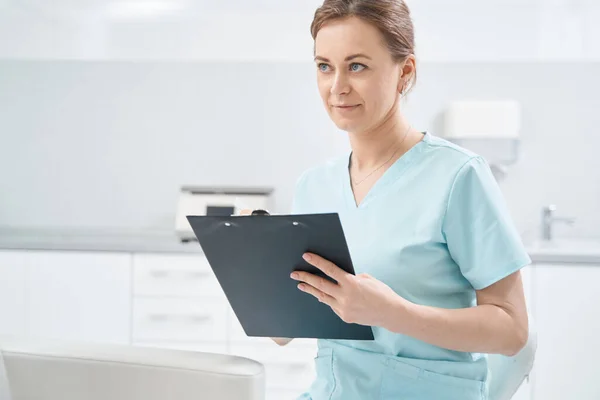 Female doctor writing on clipboard in cosmetology clinic — Photo