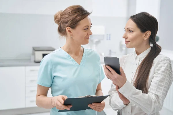 Žena používající smartphone a mluvit s lékařem v kosmetické klinice — Stock fotografie