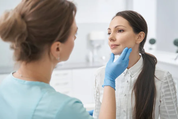Esthetische therapeut controleren vrouw gezicht huid in cosmetologie kliniek — Stockfoto