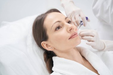 Kadın güzellik kliniğinde plastik enjeksiyon yaptırıyor.