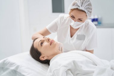 Kadın kozmetoloji kliniğinde gençleştirici güzellik iğnesi yaptırıyor.