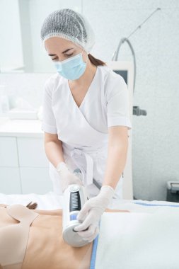 Dikkat et, kadın kozmetik uzmanı anti-selülit masajı yapıyor, karın bölgesindeki derinin sarkıklığını alıyor.