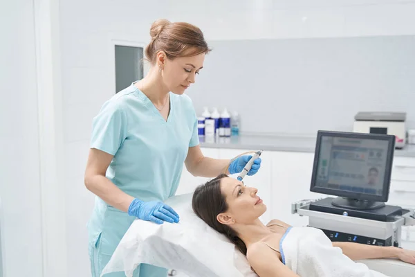 Doctor beautician performing hydrafacial treatment in clinic — Stock Photo, Image