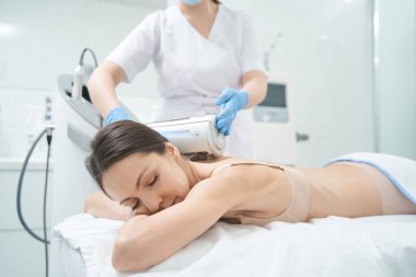 Güzellik salonunda kozmetik ameliyatı sırasında yatakta dinlenen bir kadın.