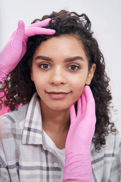 Female face is examined by medical worker with both hands — Stock Photo, Image