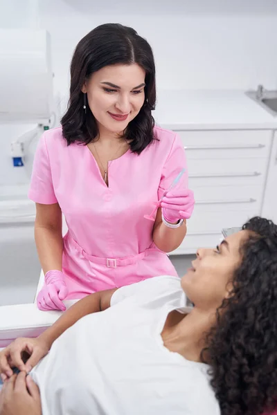 Kvinnan i medicinsk uniform visar injektionssprutan för patienten i närheten — Stockfoto