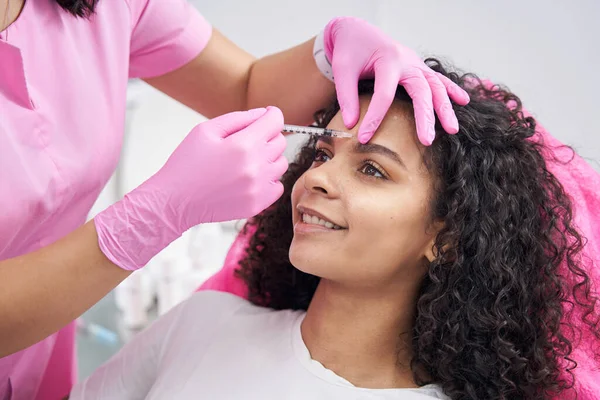 Cosmetologue effectue une procédure pour éliminer les rides du sourcil sur le visage du patient — Photo