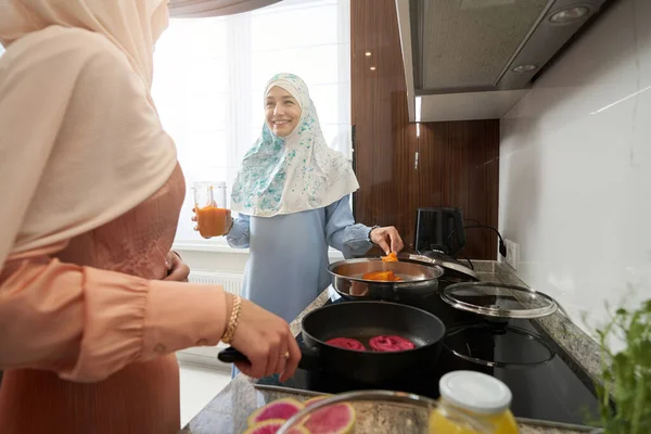 Mulher muçulmana alegre cozinhar jantar com amigo na cozinha — Fotografia de Stock