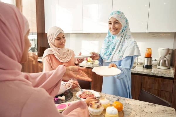 주방에서 친구들에게 접시를 주는 모슬렘 여자 — 스톡 사진